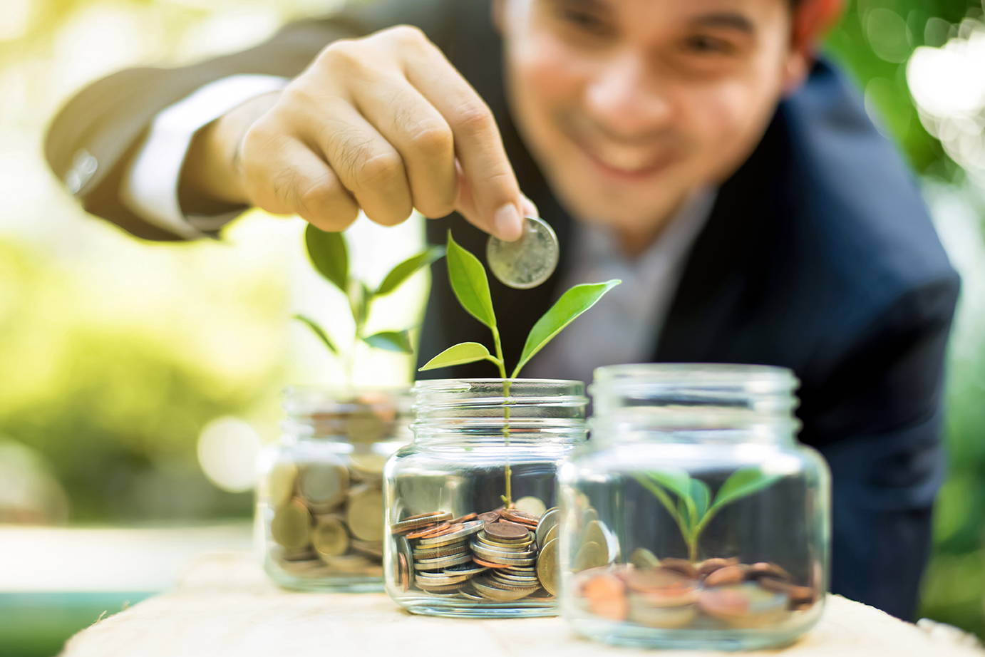 Person adding coin to glass jar