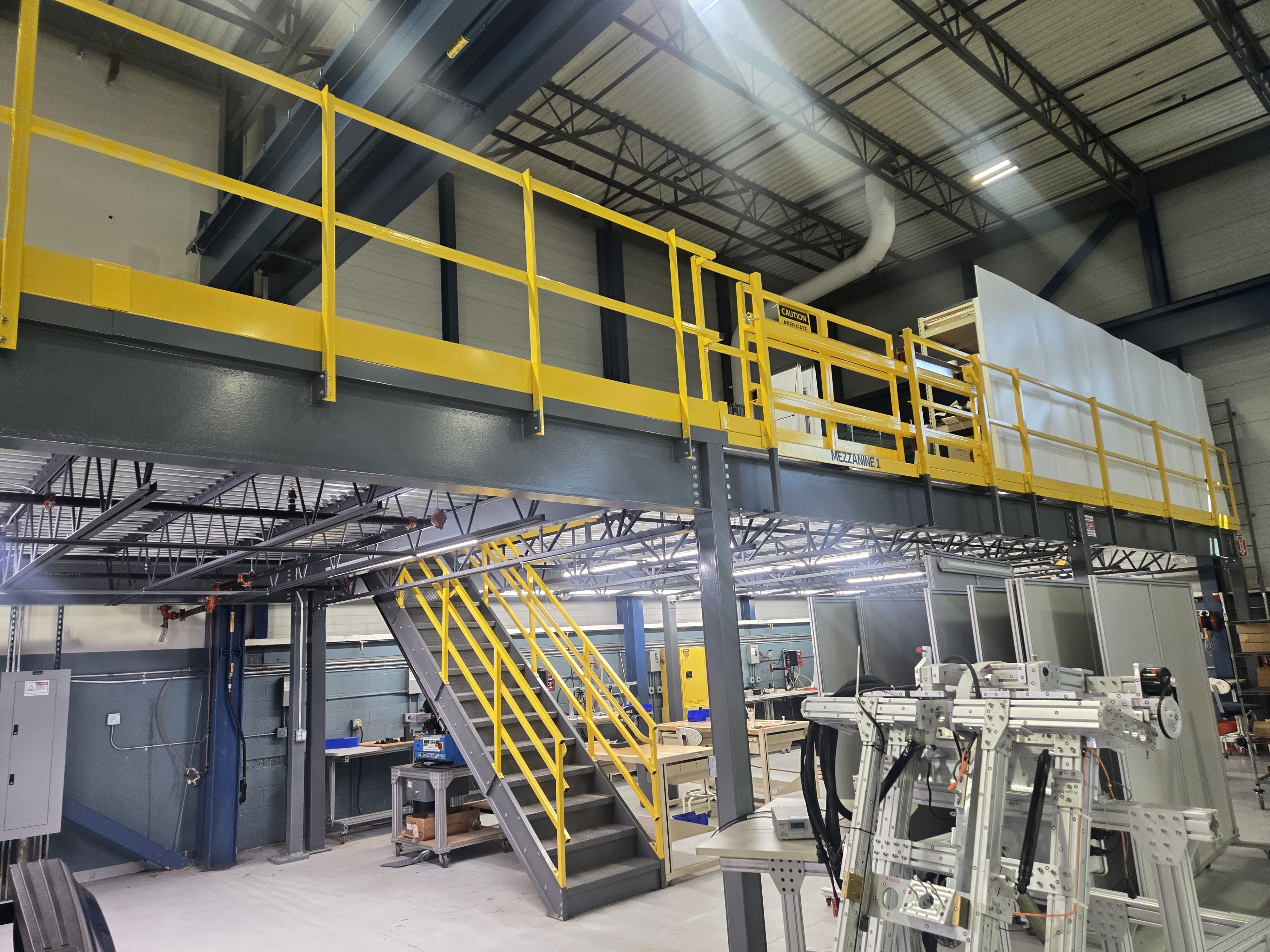 Industrial facility with a yellow-railed walkway and stairs leading to an upper level.