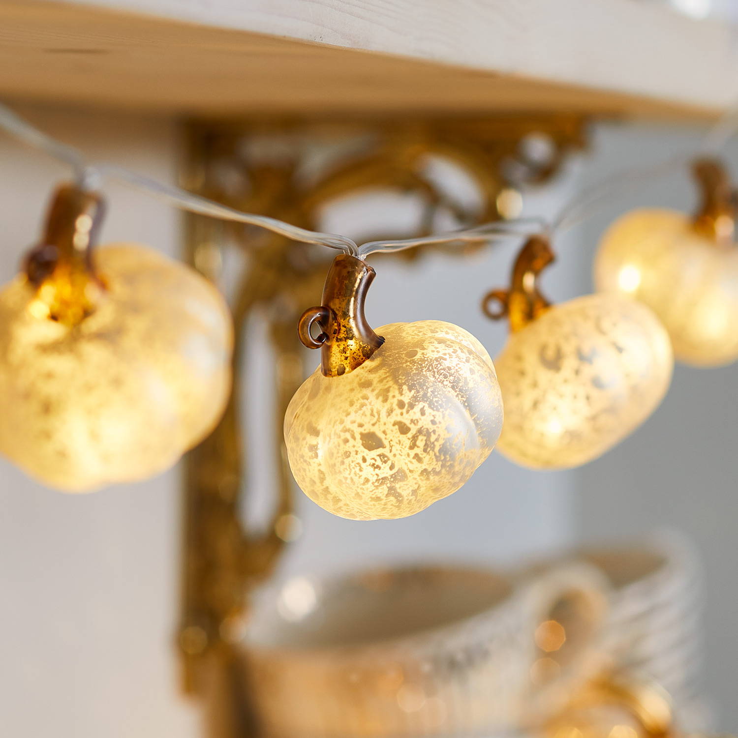 Pumpkin fairy lights hung from a wall shelf