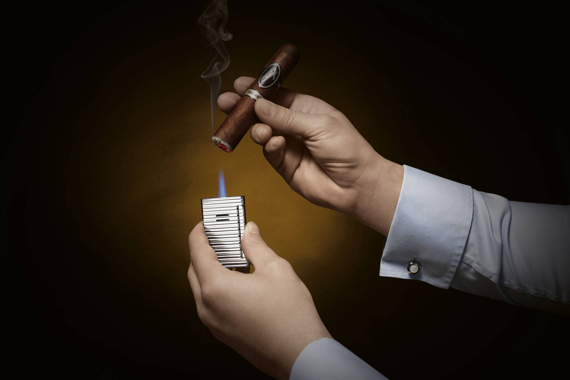 Anzünden – Nahaufnahme einer Hand, die eine Davidoff White Band Zigarre anzündet.