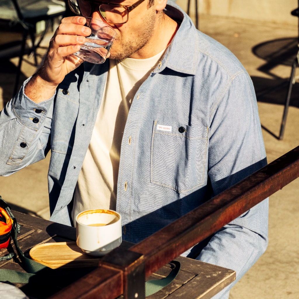 Man sipping water at a café, with coffee cup on the table.