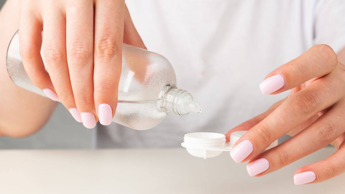 A photo of a woman holding a contact lens solution and a contact lens case