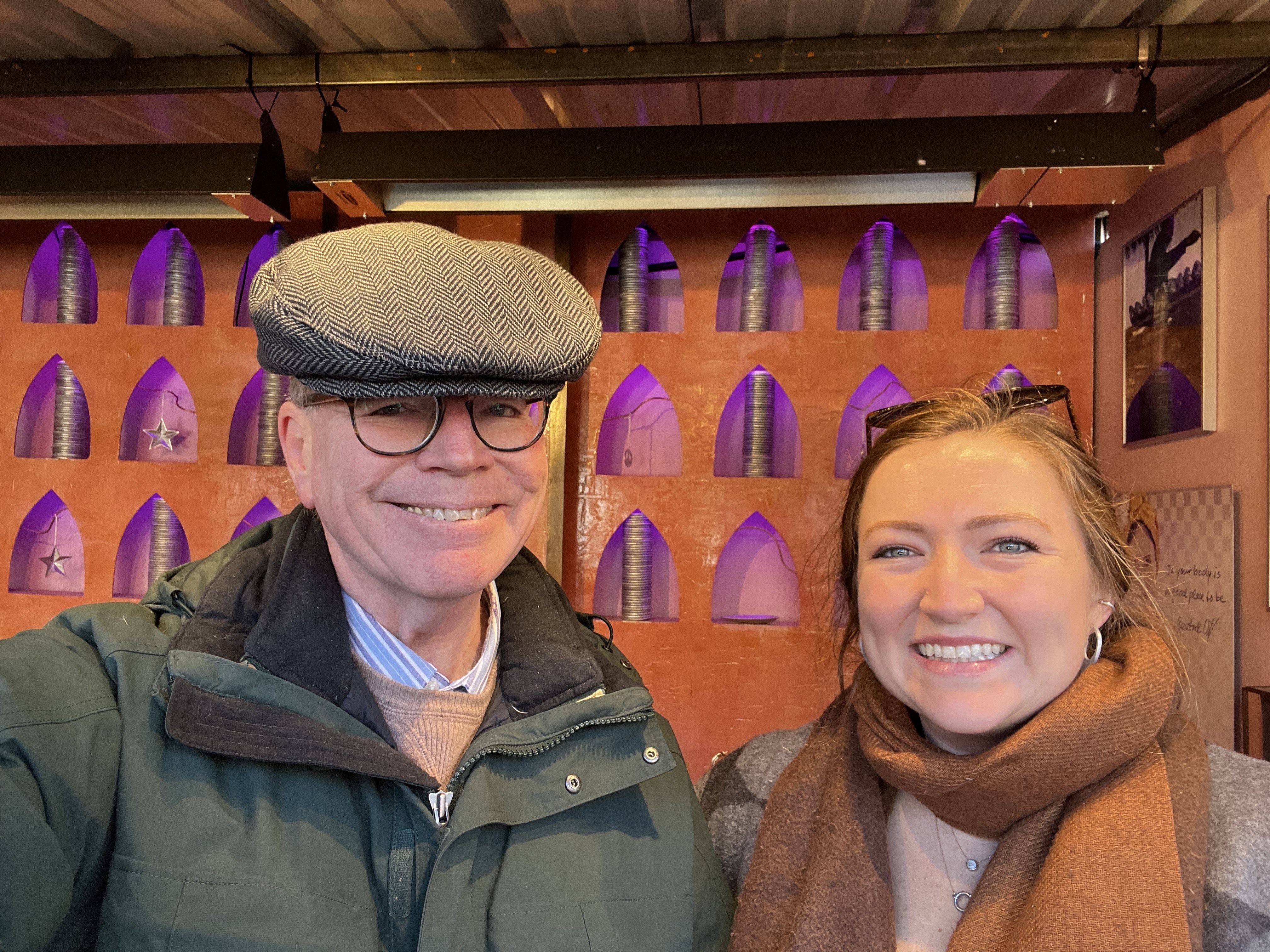 A man and a woman smiling together in front of a colorful background.