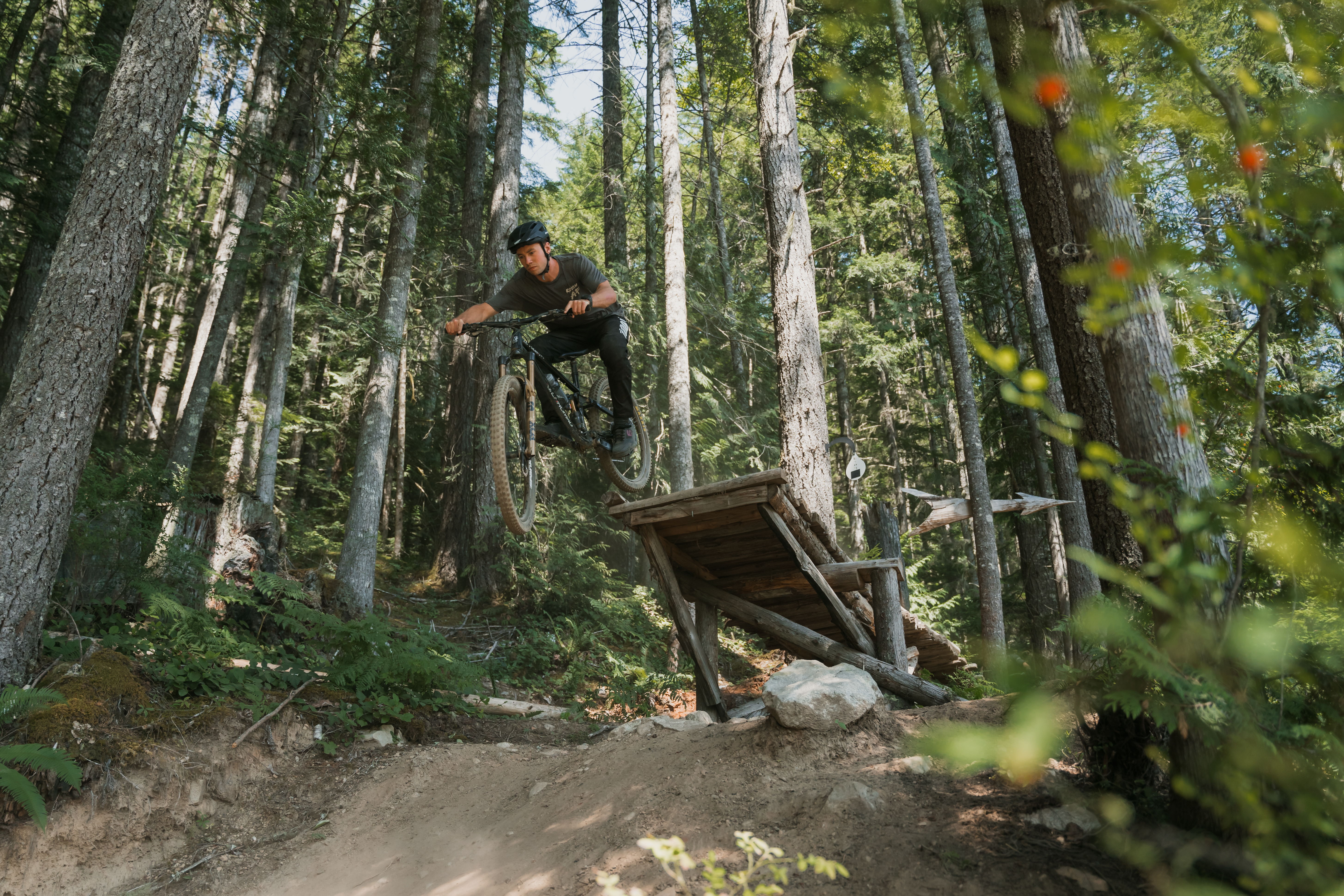 Tor dropping off a wood bridge with the Fox Transfer post on his bike