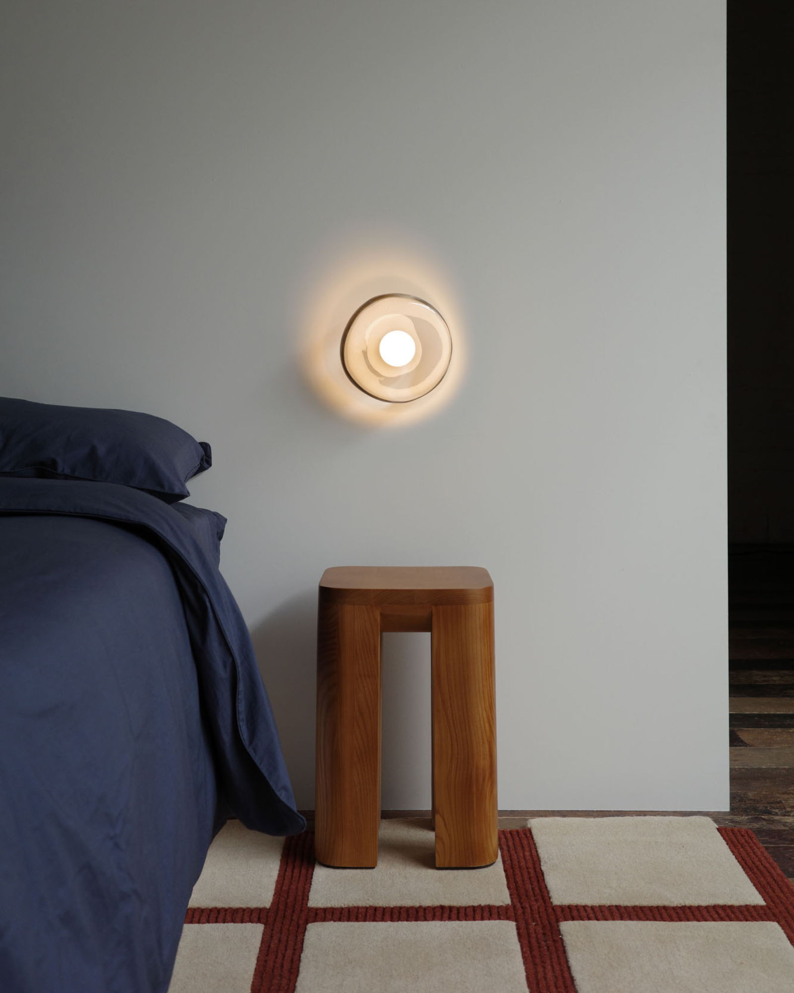 Glass Wall Sconce by Alor Studio in a bedroom
