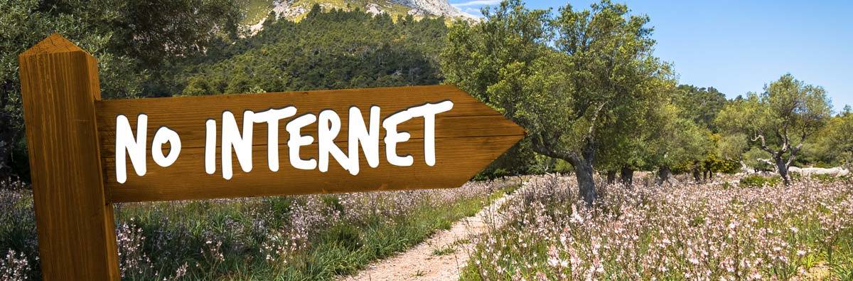 Meadow with trees and mountains in the background with a no internet sign in the foreground