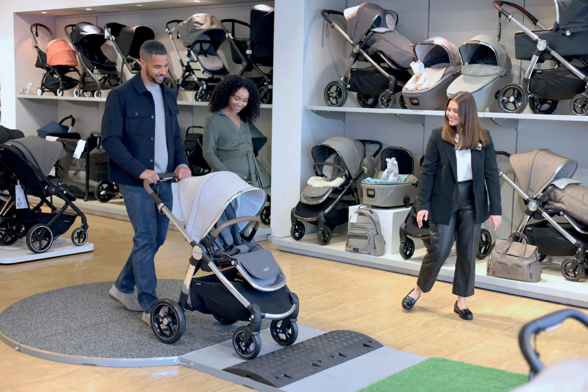 A couple testing a stroller in a store with staff nearby.