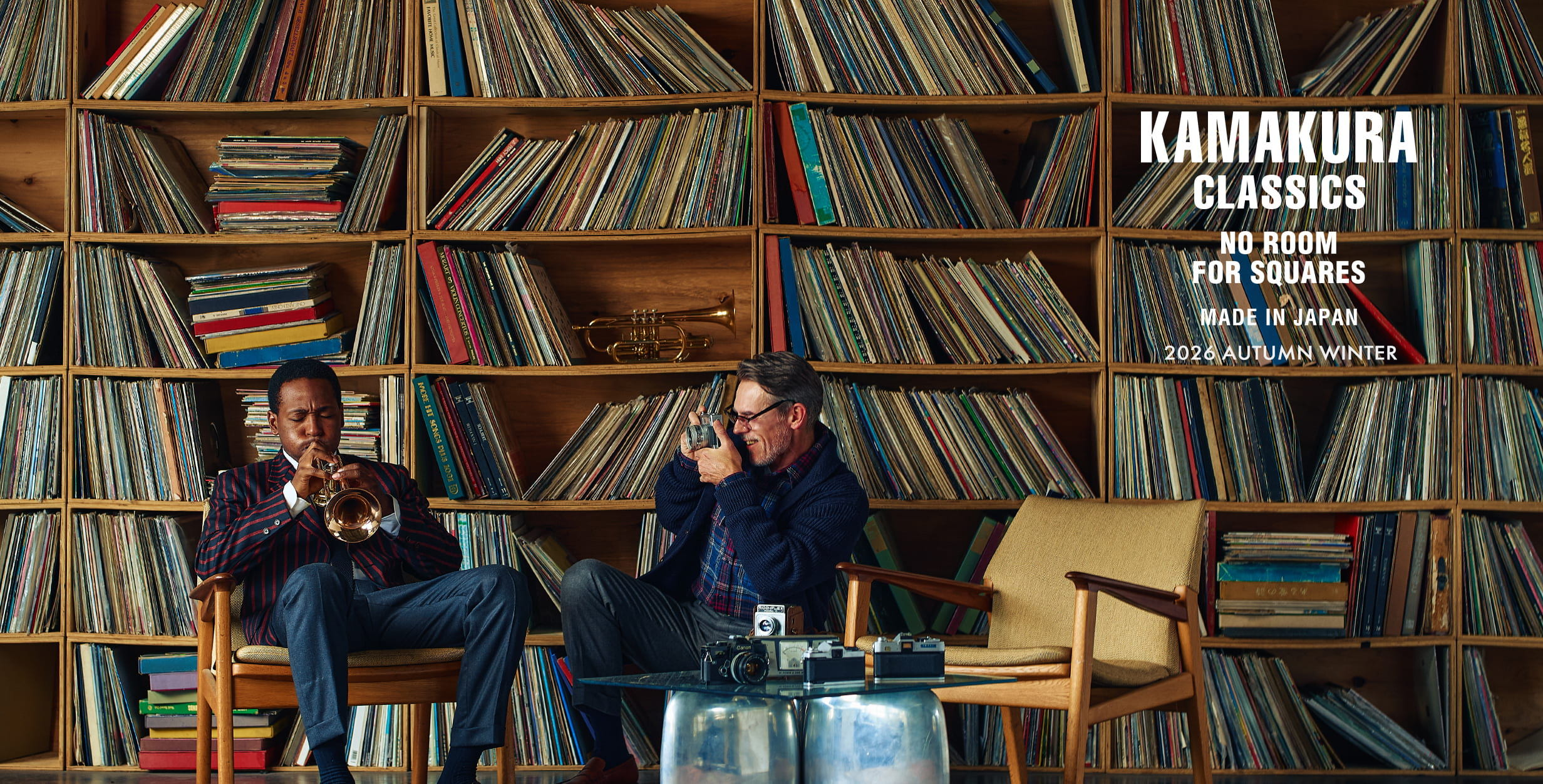 Two people sitting in front of a wall of records.