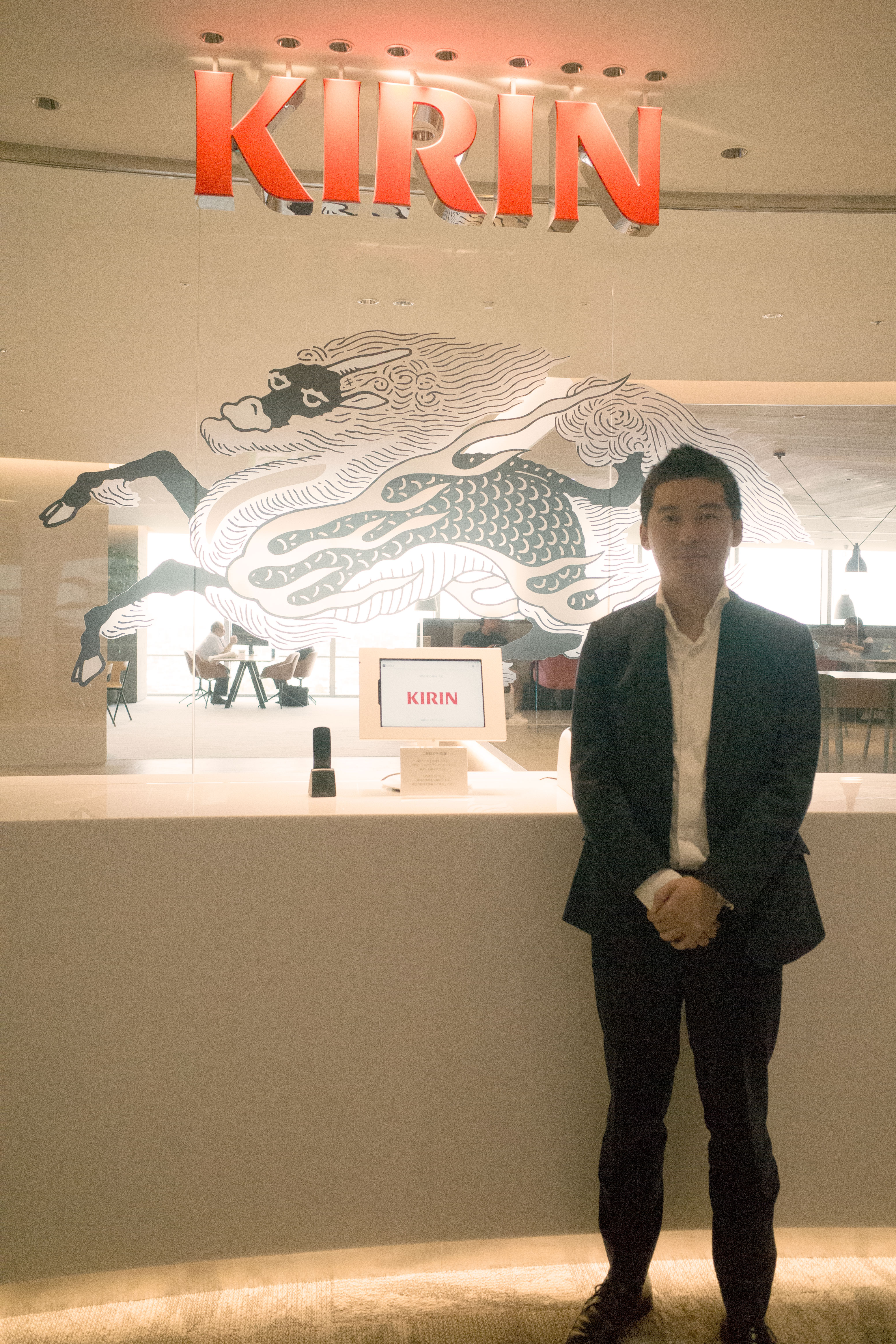A man standing in front of a Kirin sign and decorative wall.