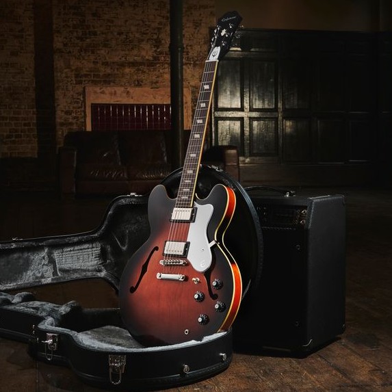 Electric guitar resting in an open case with amplifier in background.