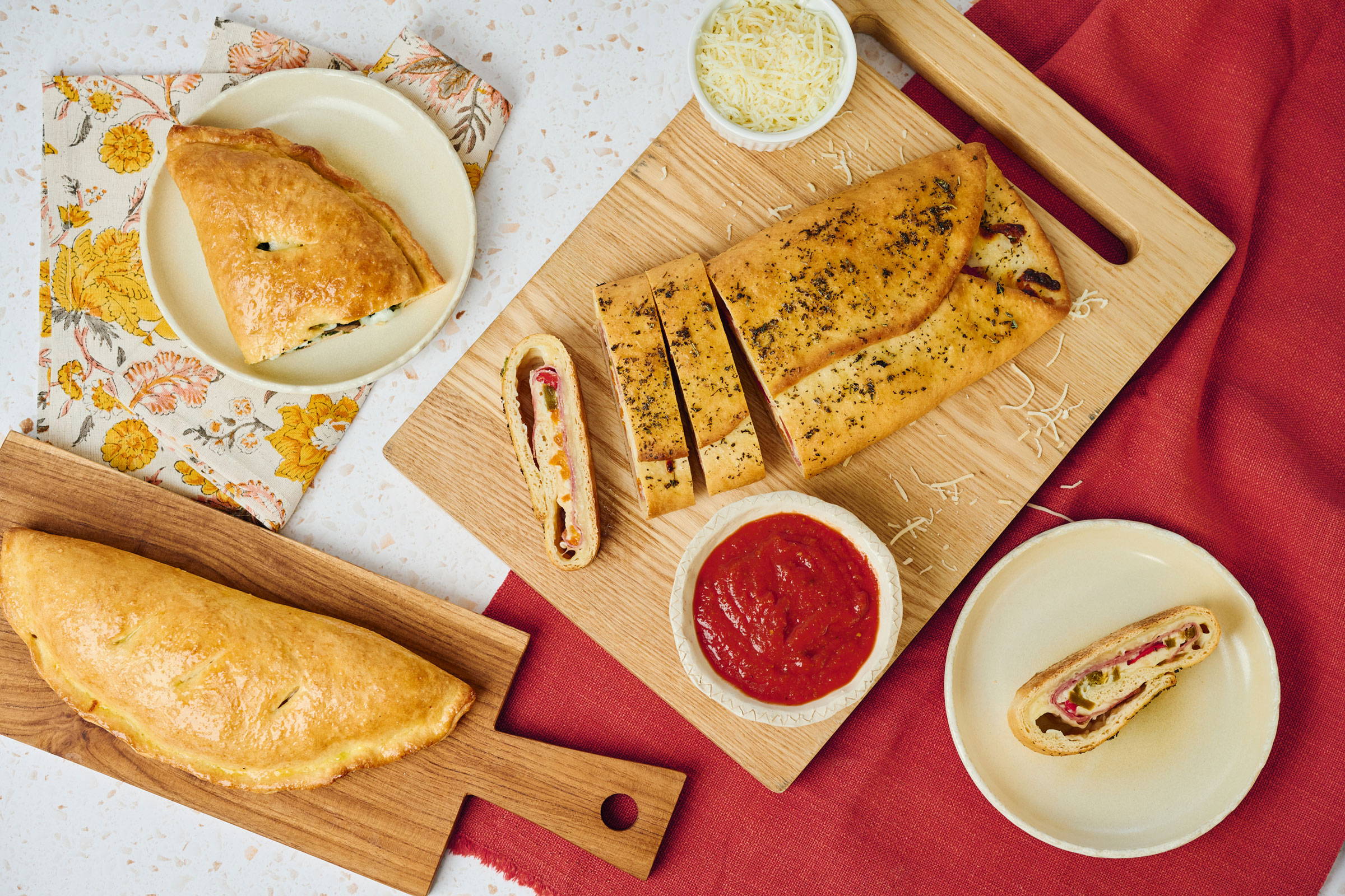 A baked calzone and stromboli sliced and on plates for serving