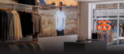 Clothing store interior with displayed garments and a mural of a man.
