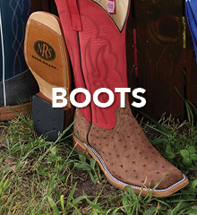 Brown cowboy boots with red accents on grass.
