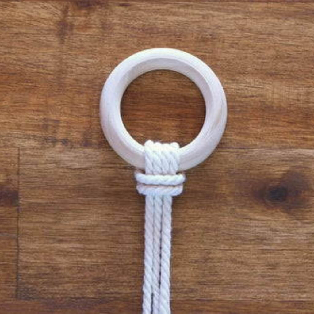 Ein Holzring mit einem Ankerknoten auf einer Holzfläche.