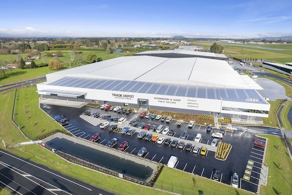 Aerial view of a large warehouse with parking and surrounding landscape.