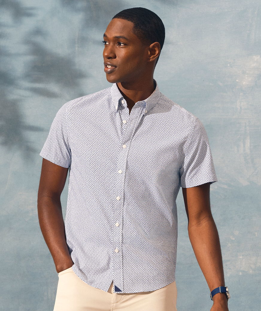 Man in a short-sleeve button-up shirt against a blue background.