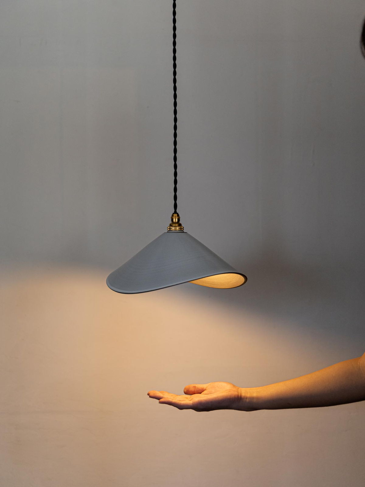 A pendant lamp hanging above a hand reaching out.