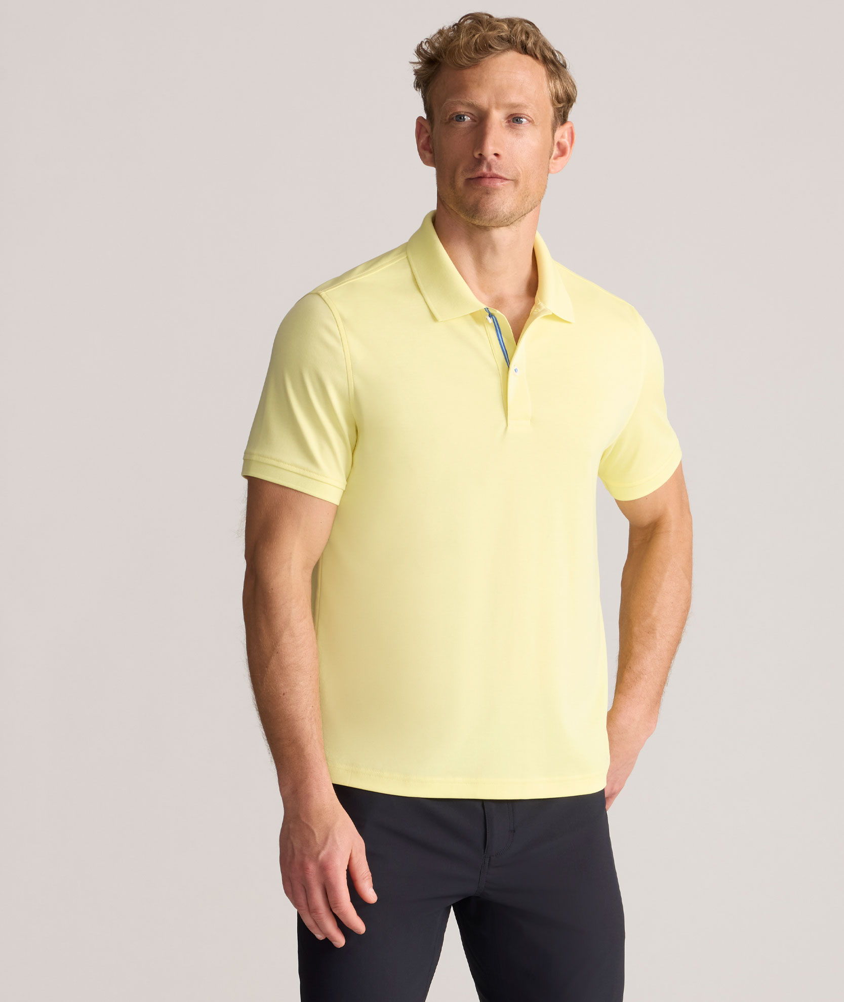 Man wearing a yellow polo shirt and black pants.