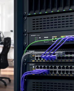 Data center rack with networking cables and office chair in the background.