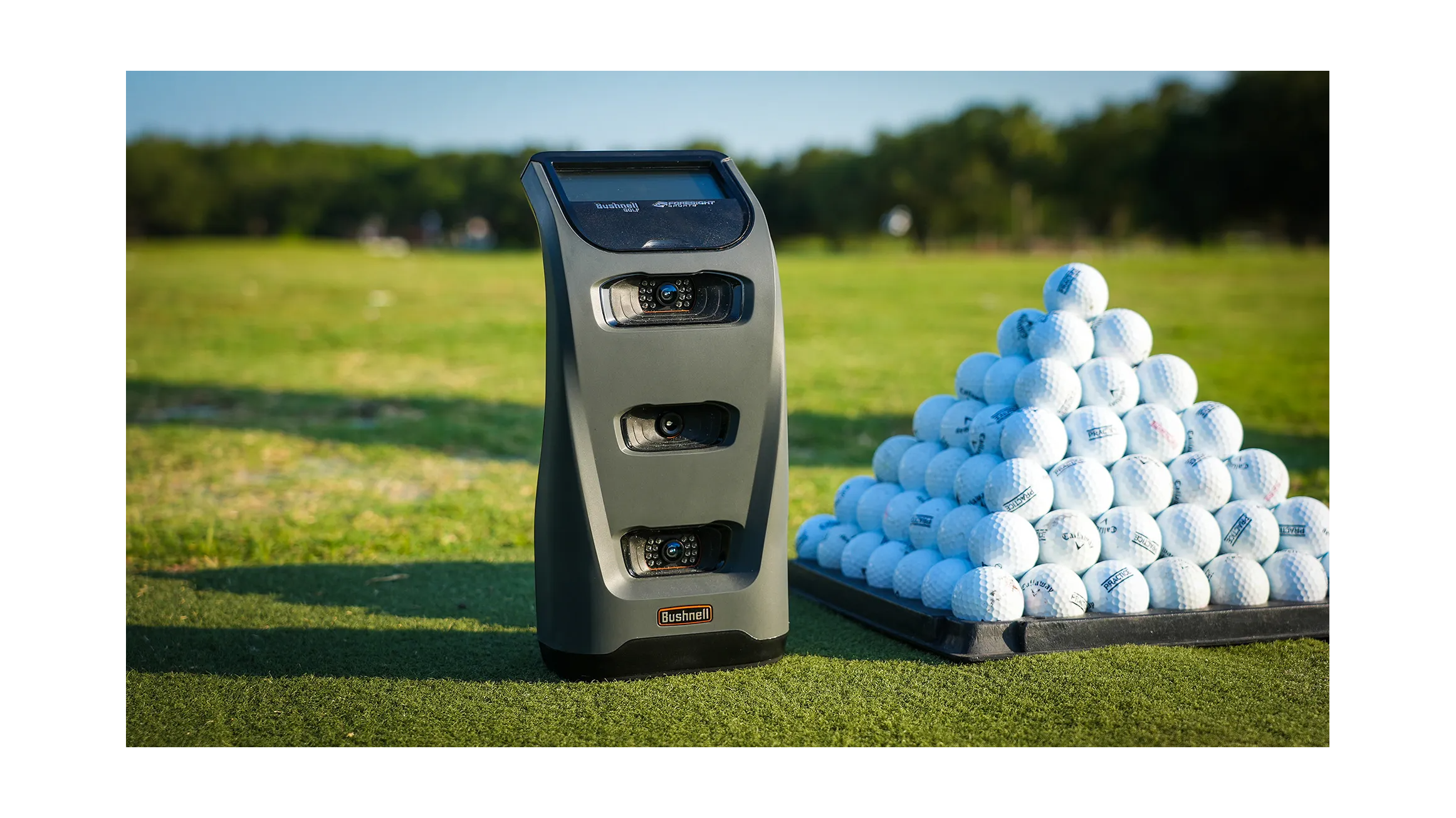 Bushnell Launch Pro next to a stack of golf balls  at the range