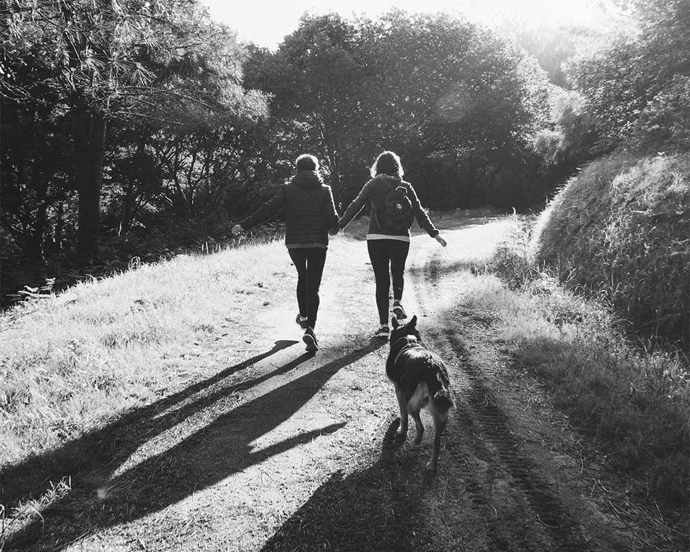 Black and white photo of a couple hiking with their dog