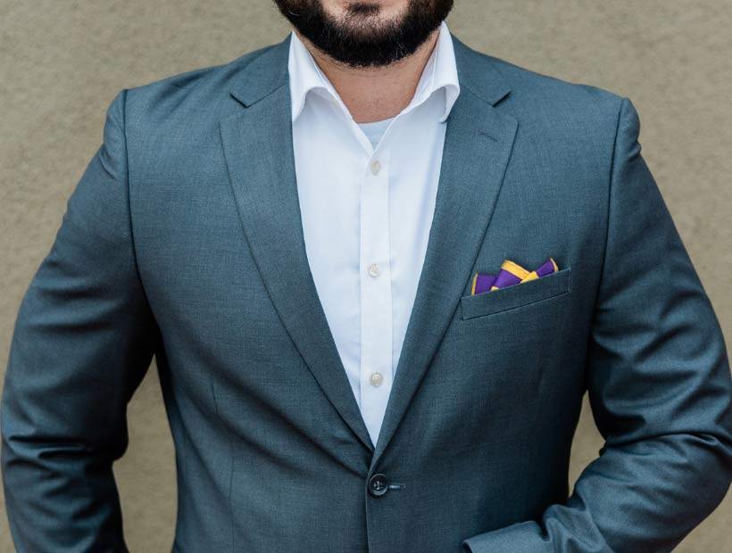 Man wearing a suit, white button down and striped pocket square folded with 3 points