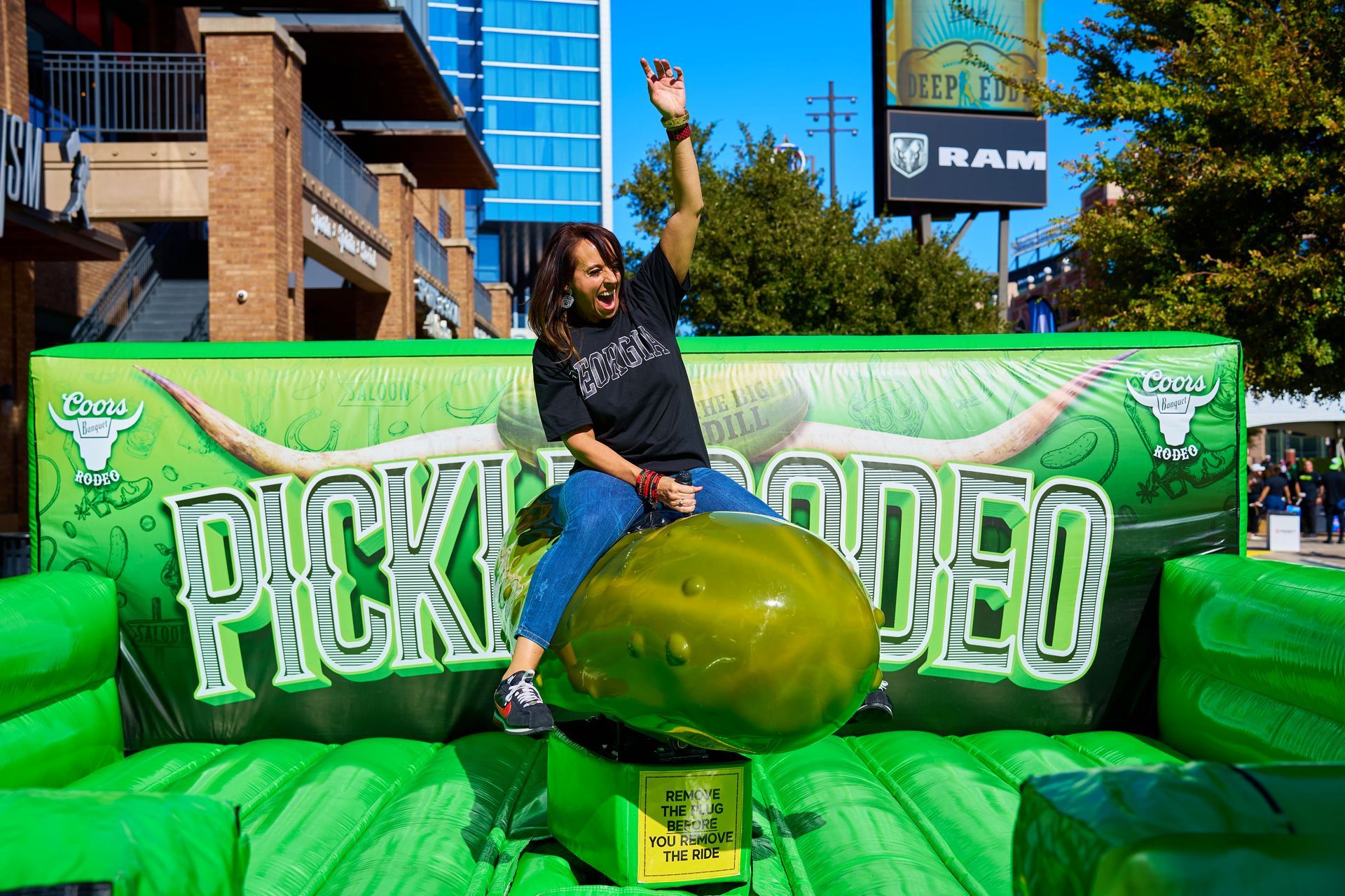 A festival guest celebrates a successful ride on the Coors Banquet Pickle Rodeo mechanical pickle activation at The Big Dill pickle festival, Globe Life Field and Texas Live!, Arlington Texas 2025.