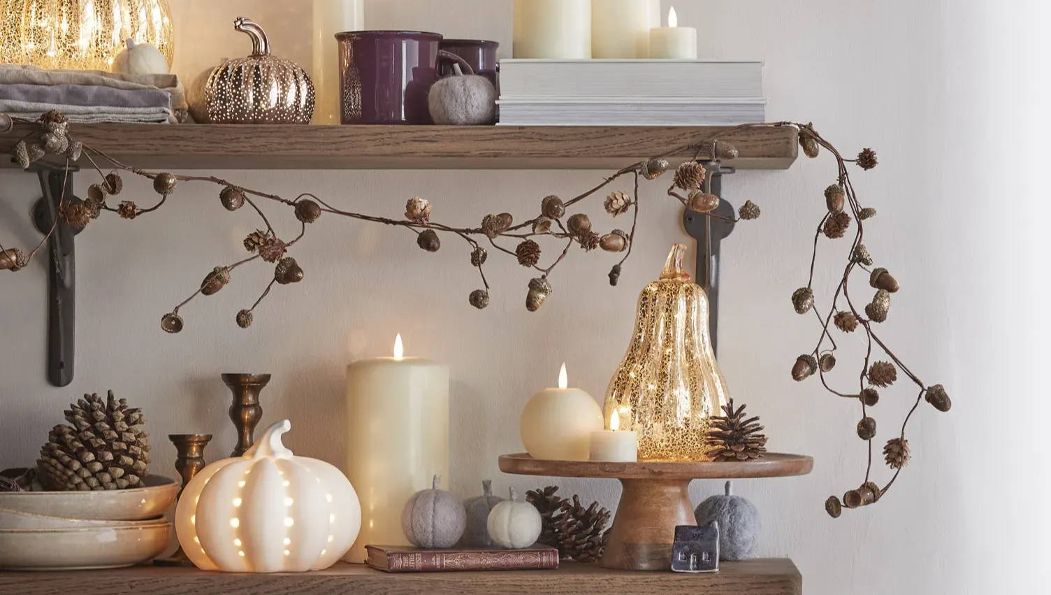 An autumnal shelf setting with an autumn garland and pumpkin decor.