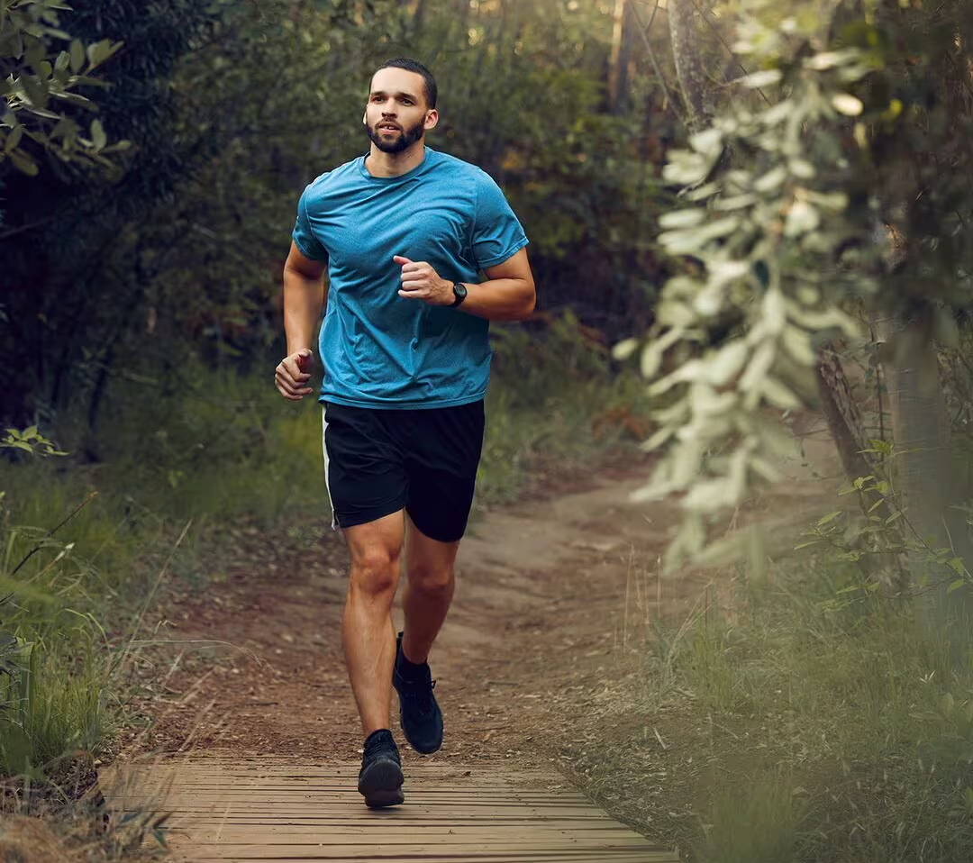 Muž v športových šortkách a tričku si užíva víkendový beh v lese - musí mať svoju alergickú nádchu pod kontrolou