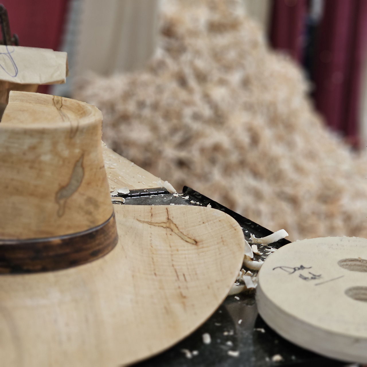 Woodworking tools and materials for hat making on a workbench.