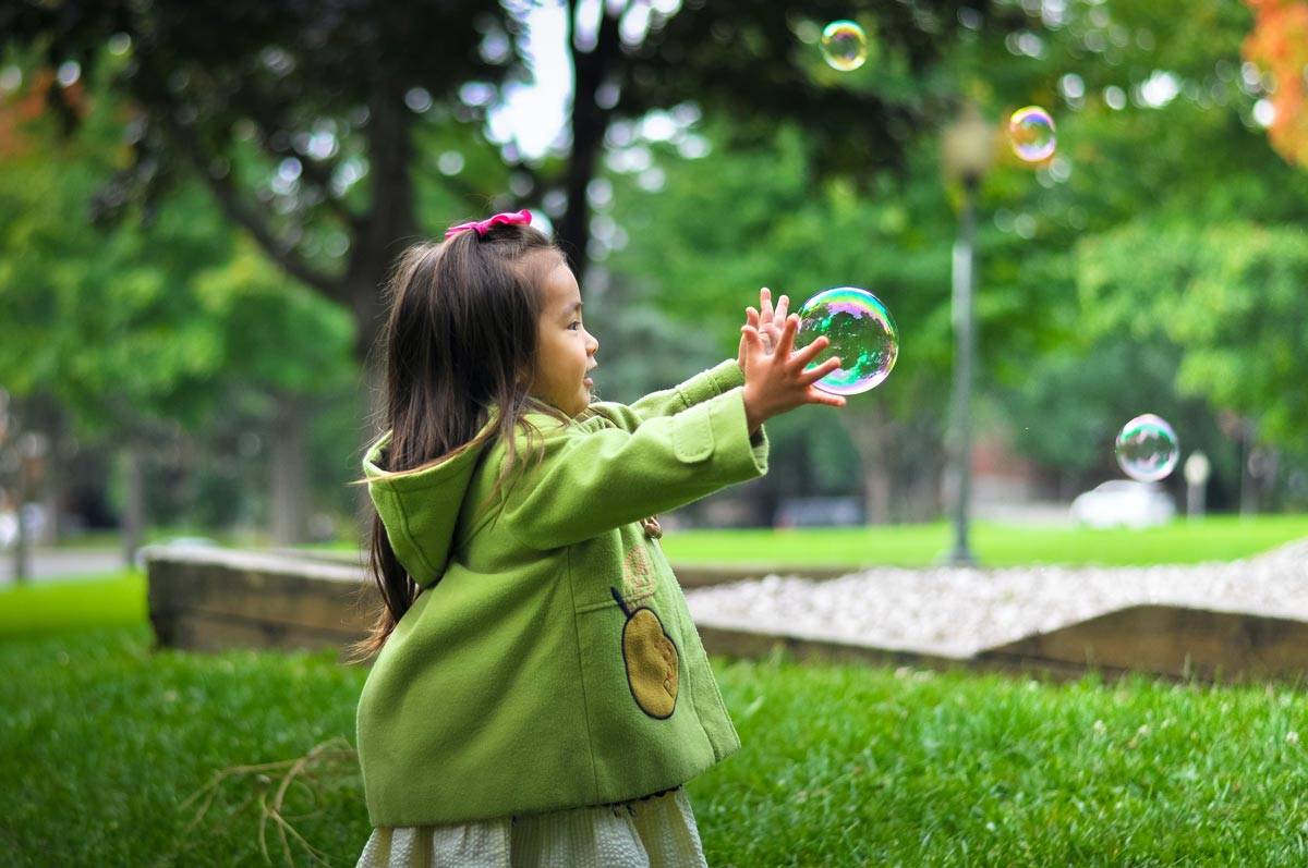 A young girl changing bubbles in a park