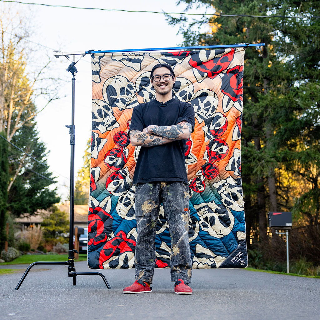 Bryce Wong standing in front of the Skulls & Roses Original Puffy Blanket