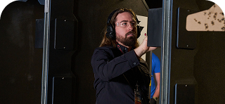 Man adjusting equipment in a shooting range, wearing headphones.