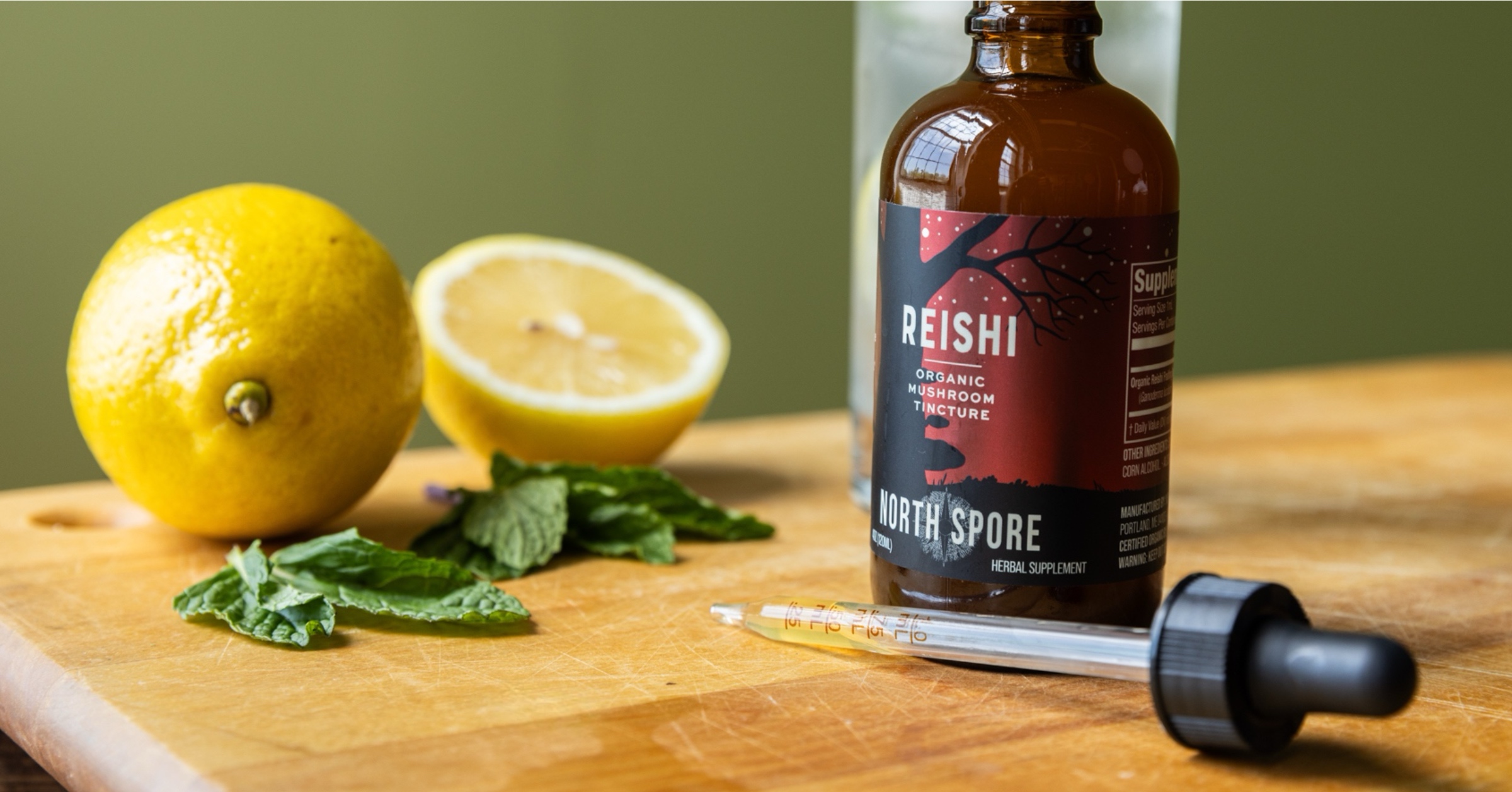 Brown bottle with dropper, lemon, and mint on a wooden surface.