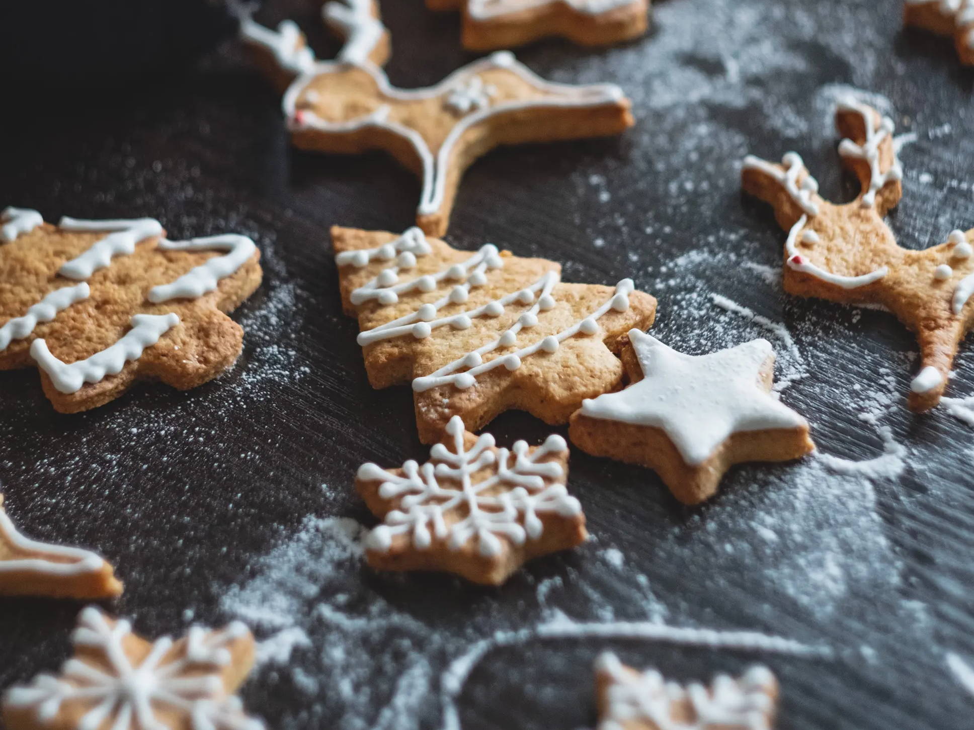Iced and decorated gingerbread cookies on a counter dusted with flour