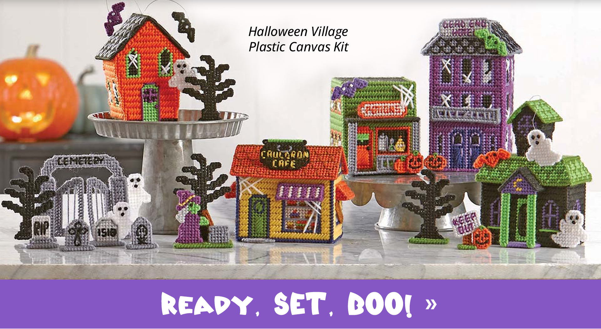 Halloween-themed village decorations with spooky houses and a pumpkin.