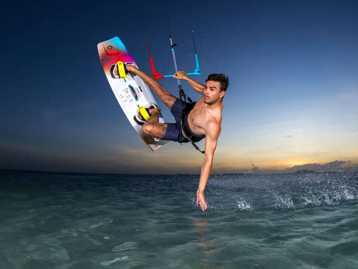 Person kitesurfing at sunset over the ocean.