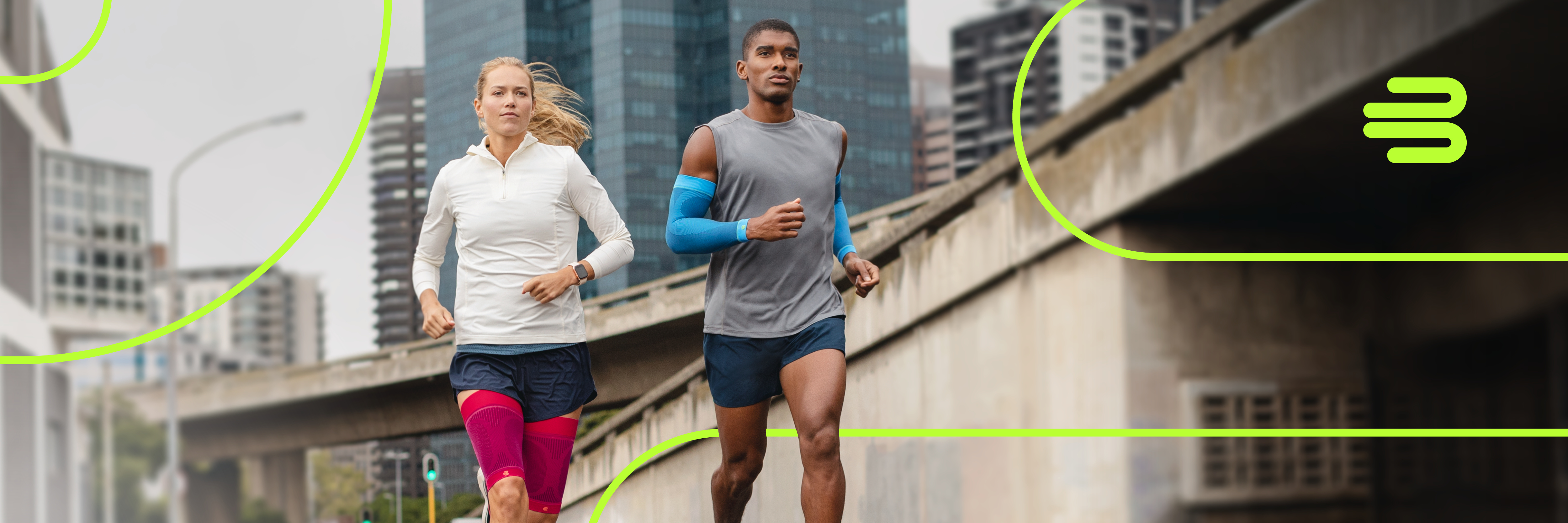 Two runners jogging on a city street, wearing athletic clothing.