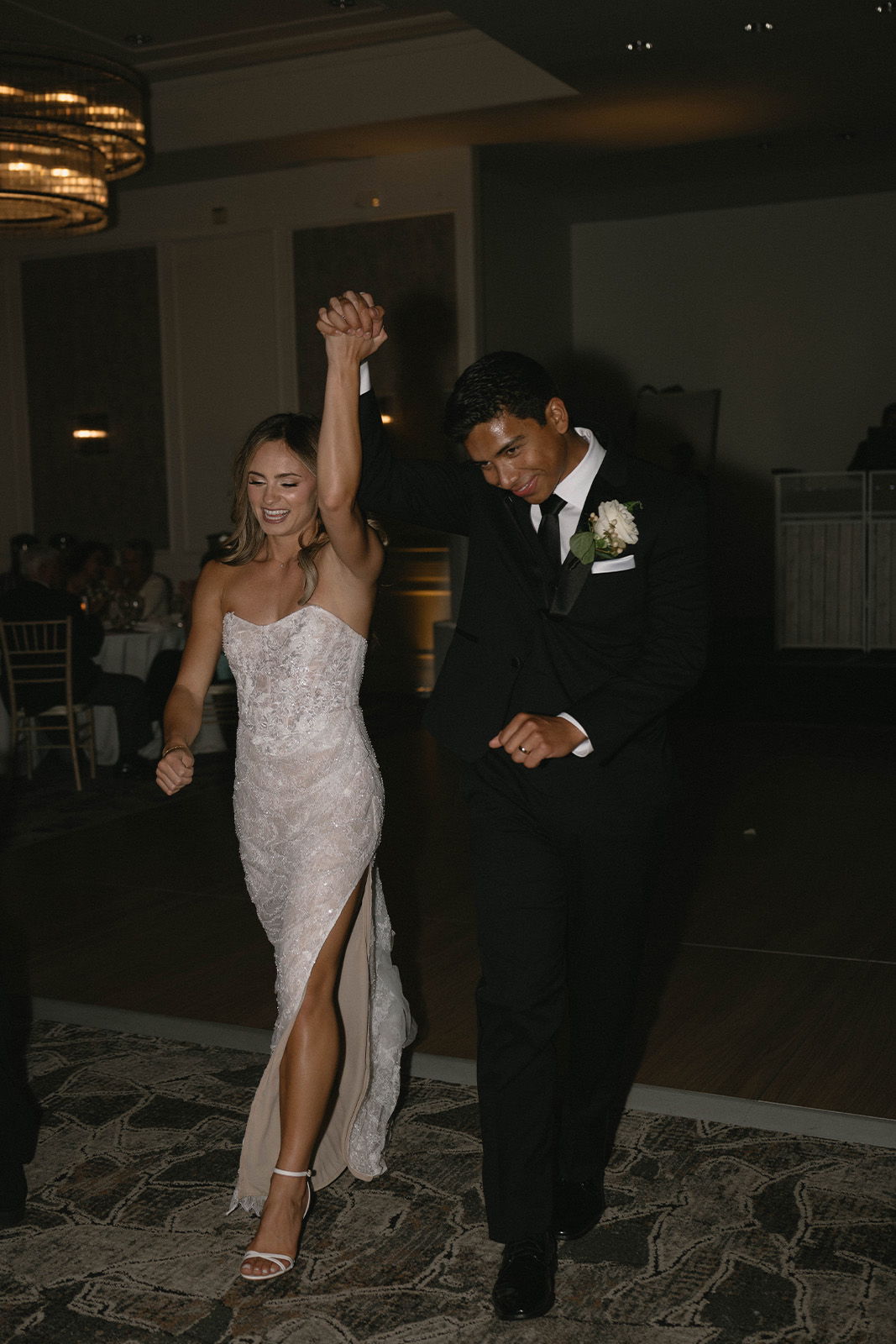 Couple joyfully entering a venue, dressed elegantly for a special occasion.