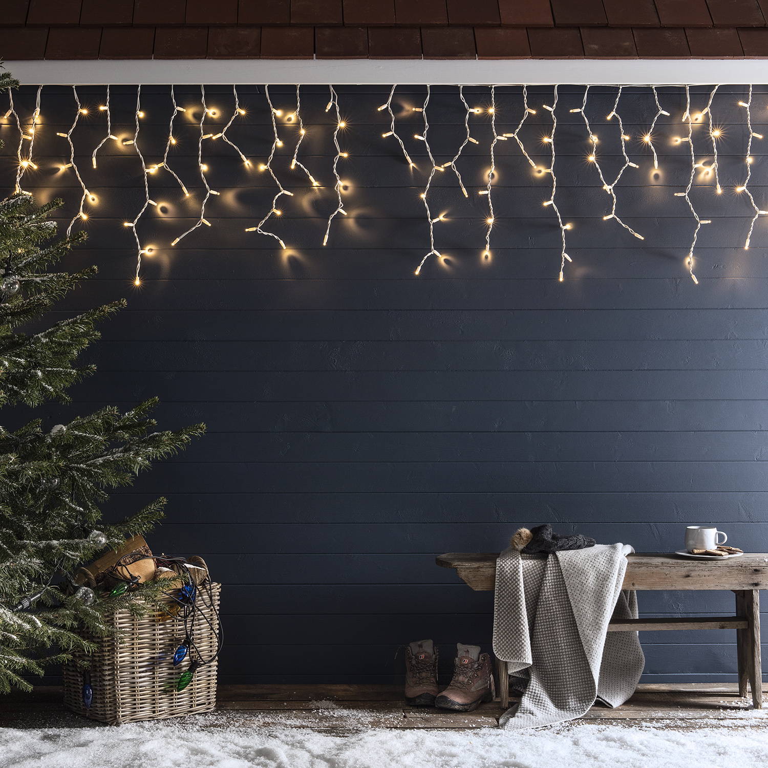 Warm white icicle lights hanging from a snowy winter cabin
