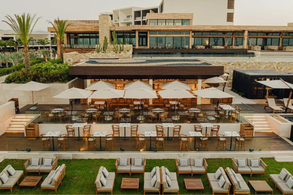 Luxury resort outdoor dining terrace with commercial tables and chairs, umbrellas, lounge seating, and landscaped areas 