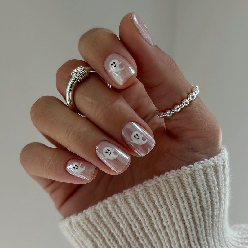 A hand with stylish nails and rings, wearing a knitted sweater.