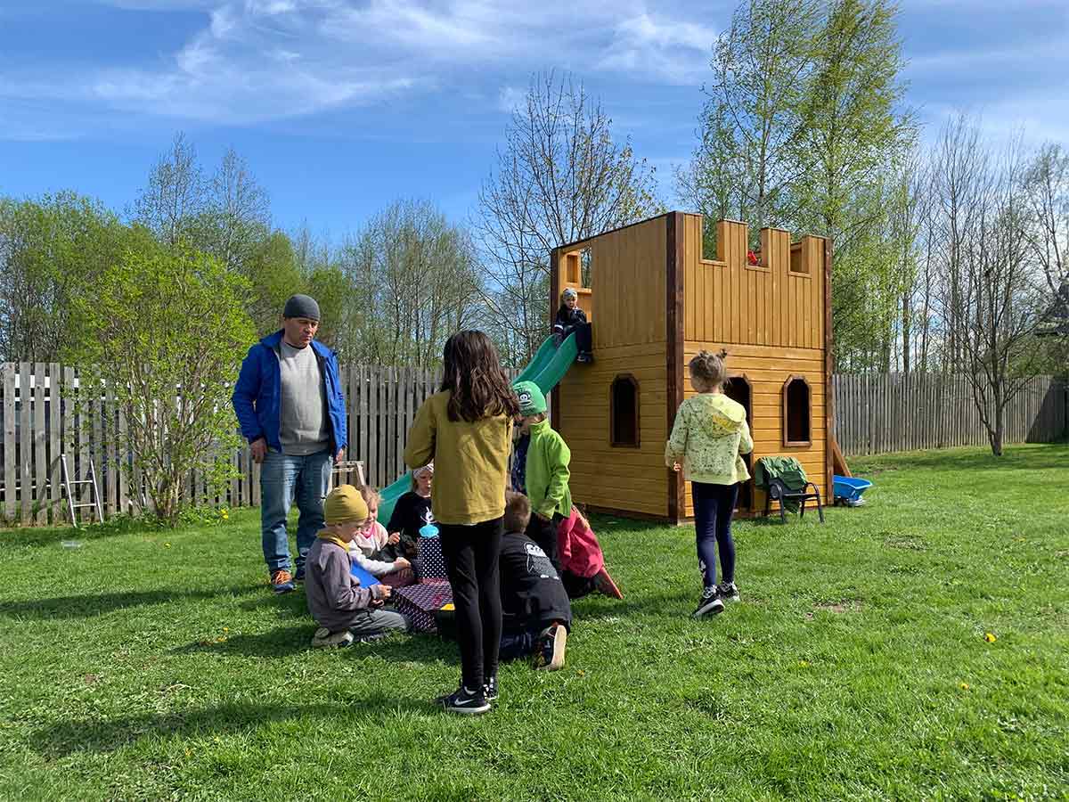 Outside view with Custom Castle Playhouse and kids in the backyard by WholeWoodPlayhouses 