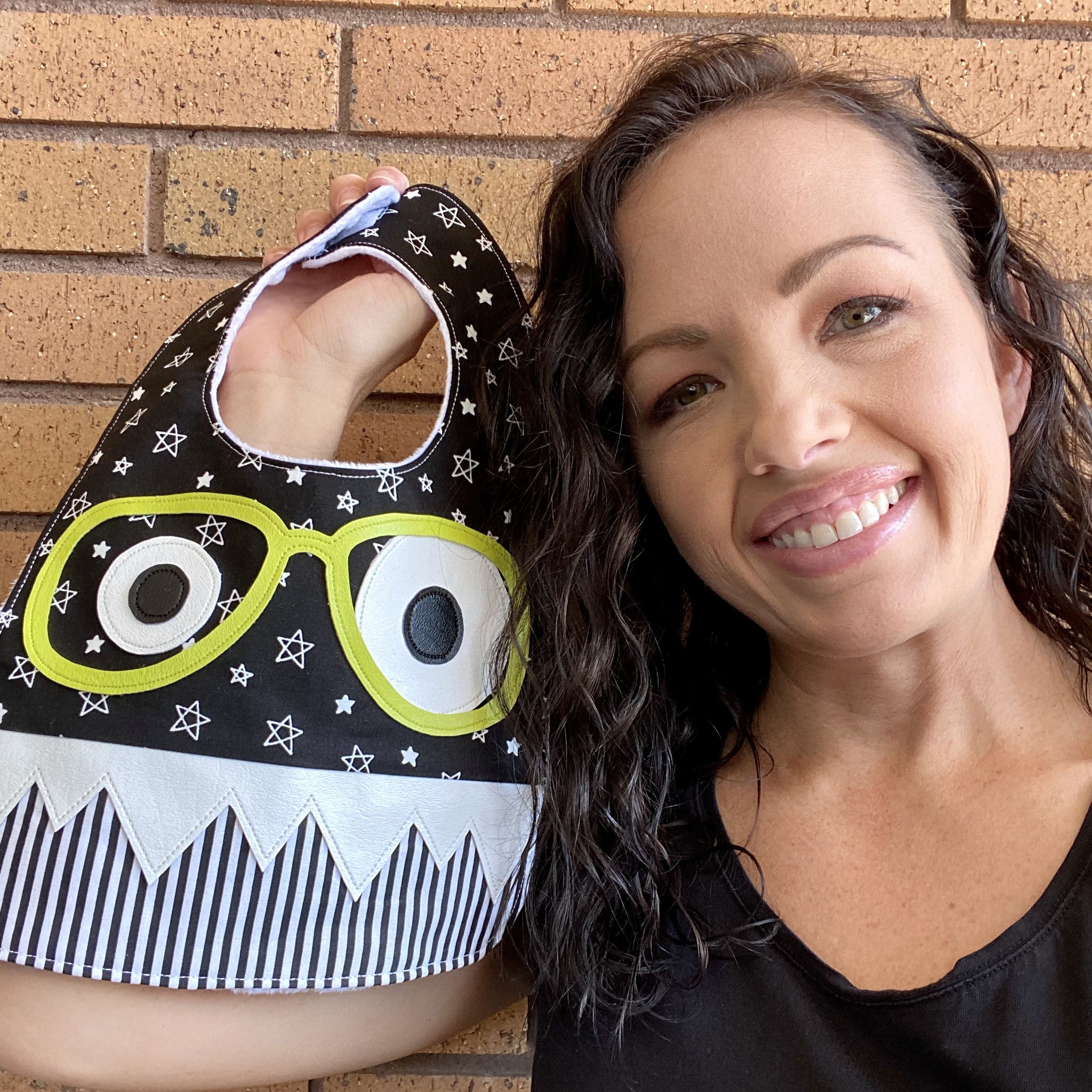 Smiling woman holding a black and white patterned bag with eyes.