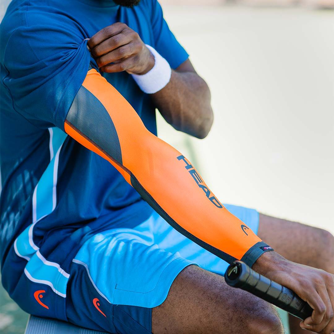 A tennis player slides on his HEAD™ x eSmartr smart compression sleeve for better focus as he begins his match.