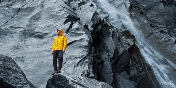 Man in mountains using a The North Face yellow shell jacket.