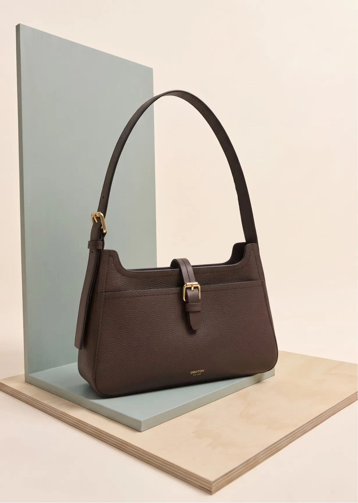 A brown handbag displayed on a minimalistic stand.