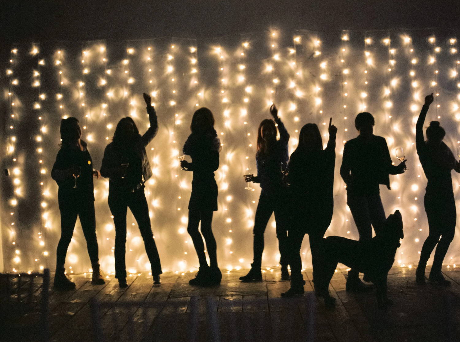 human figures silhouetted in front of LED curtain lights