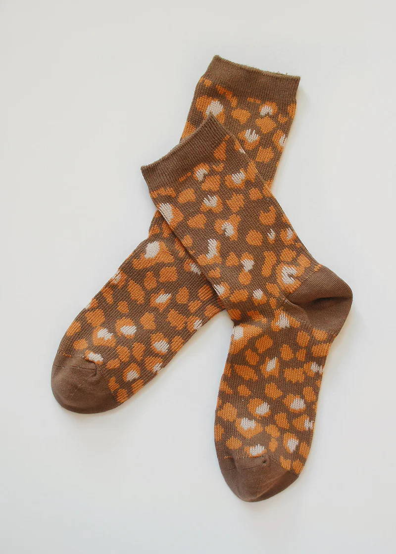 A pair of brown and orange crew socks with a leopard print pattern