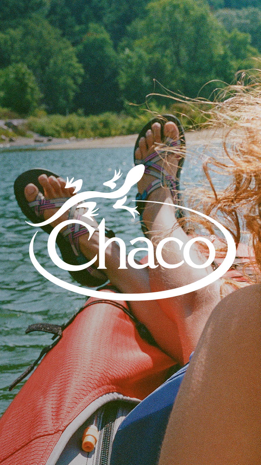 Young woman wearing Chacos resting feet on side of kayak in the middle of a lake